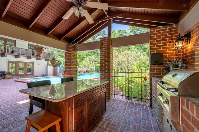 view of patio / terrace with ceiling fan, exterior kitchen, exterior bar, an outdoor pool, and a grill