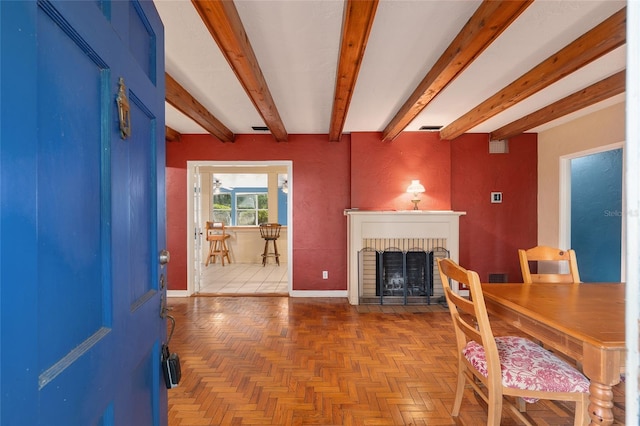 living room featuring baseboards, beamed ceiling, a brick fireplace, and visible vents