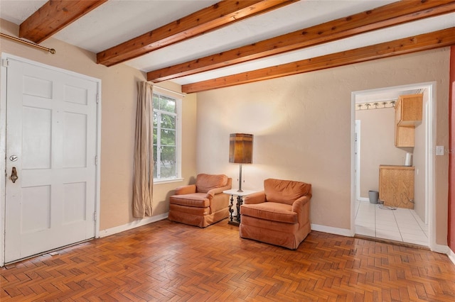 living area featuring baseboards and beamed ceiling