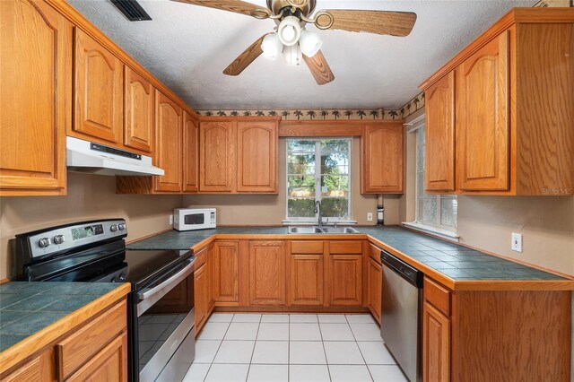 kitchen with brown cabinetry, visible vents, appliances with stainless steel finishes, a sink, and under cabinet range hood