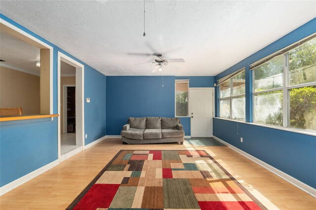living room with a textured ceiling, ceiling fan, wood finished floors, and a healthy amount of sunlight
