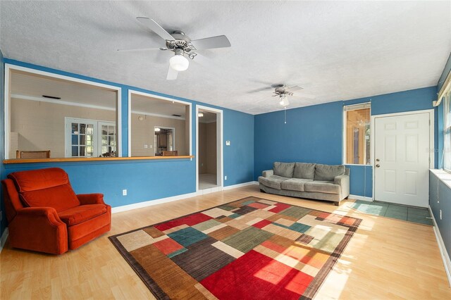 living room with baseboards, a textured ceiling, ceiling fan, and wood finished floors