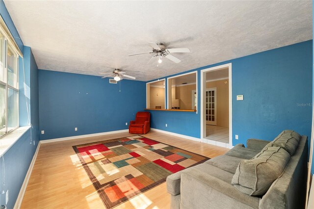 unfurnished living room with a ceiling fan, baseboards, wood finished floors, and a textured ceiling