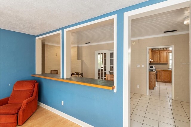 kitchen with baseboards, brown cabinetry, light tile patterned flooring, and a textured ceiling