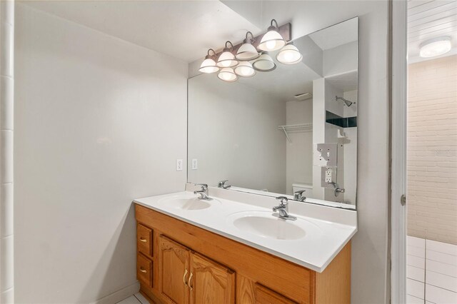 bathroom featuring a sink, walk in shower, toilet, and double vanity