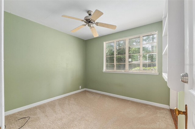 carpeted empty room featuring baseboards and ceiling fan