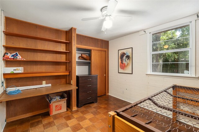 bedroom featuring dark floors, ceiling fan, and wood walls