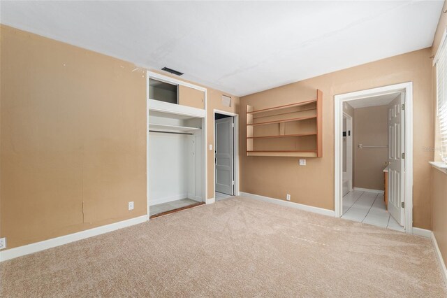 unfurnished bedroom featuring carpet floors, baseboards, ensuite bath, and a closet