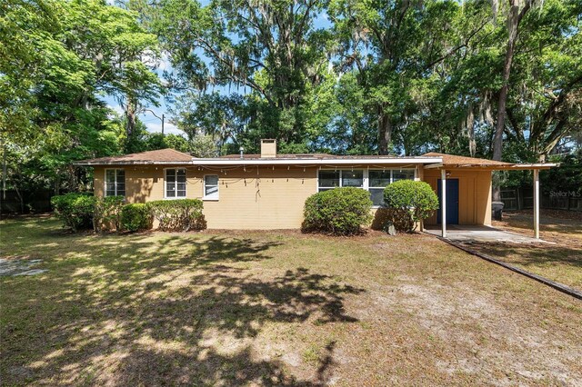 ranch-style home with fence, a chimney, an attached carport, and a front lawn