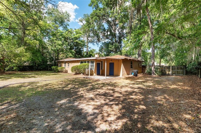 back of house featuring a fenced backyard, a chimney, and a yard