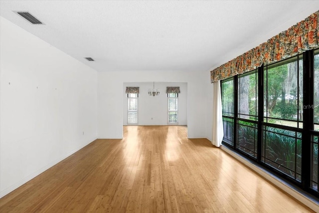 3925 NW 35th Pl, Gainesville, FL 32606 - empty room featuring baseboards, a notable chandelier, light wood finished floors, and visible vents