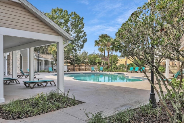 community pool with a patio area and fence