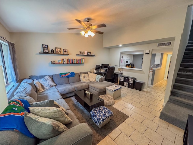 living area featuring stairway, tile patterned floors, a ceiling fan, and visible vents