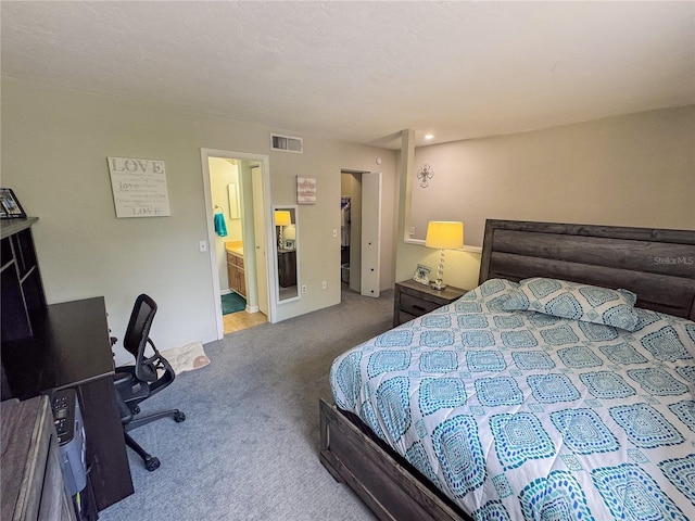 carpeted bedroom with visible vents and ensuite bath