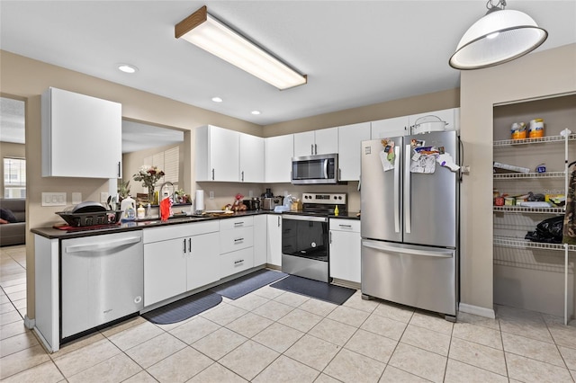 4586 SW 48th Way Unit 106, Gainesville, FL 32608 - kitchen featuring dark countertops, appliances with stainless steel finishes, light tile patterned floors, white cabinets, and recessed lighting