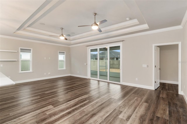 unfurnished room with a raised ceiling, ceiling fan, ornamental molding, and dark wood finished floors
