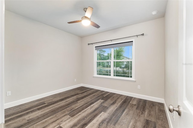 empty room with baseboards, a ceiling fan, and dark wood-style flooring