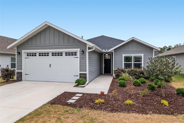 view of front of property with board and batten siding, driveway, an attached garage, a shingled roof, and stone siding