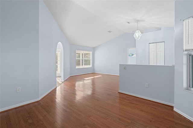 1017 NW 87th Way, Gainesville, FL 32606 - unfurnished living room featuring visible vents, arched walkways, vaulted ceiling, wood finished floors, and baseboards