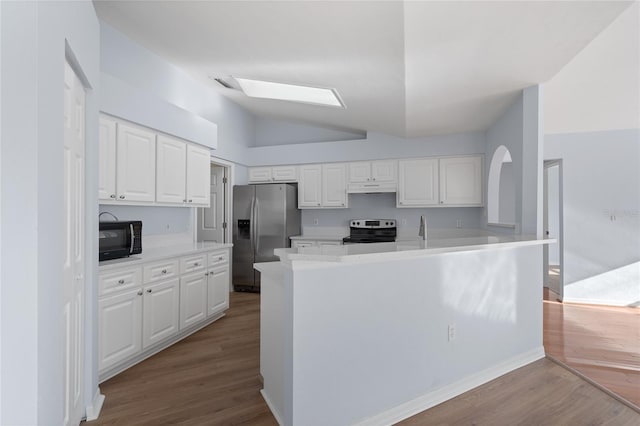 1017 NW 87th Way, Gainesville, FL 32606 - kitchen featuring wood finished floors, under cabinet range hood, white cabinets, appliances with stainless steel finishes, and vaulted ceiling