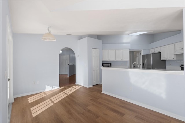 1017 NW 87th Way, Gainesville, FL 32606 - kitchen with wood finished floors, baseboards, white cabinetry, stainless steel fridge with ice dispenser, and arched walkways