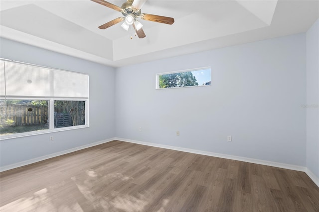 1017 NW 87th Way, Gainesville, FL 32606 - spare room featuring baseboards, ceiling fan, a tray ceiling, and wood finished floors