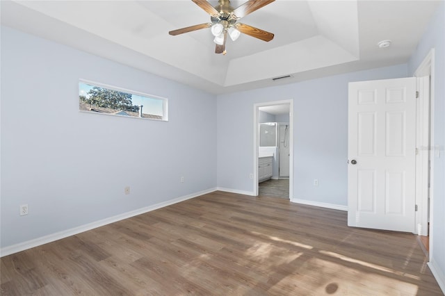 1017 NW 87th Way, Gainesville, FL 32606 - unfurnished bedroom with connected bathroom, baseboards, wood finished floors, a tray ceiling, and visible vents