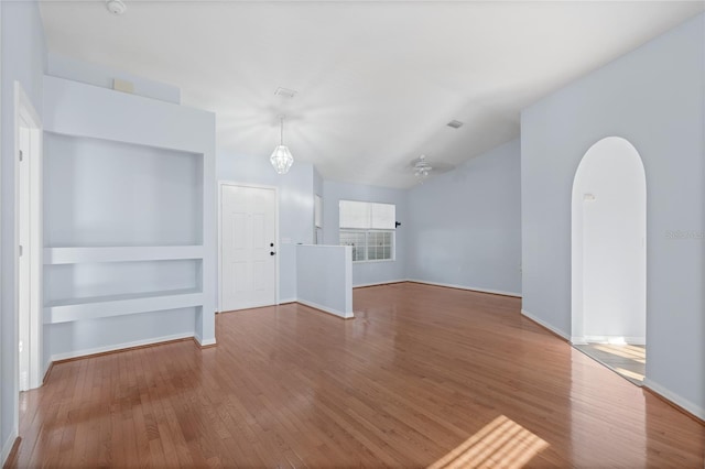 1017 NW 87th Way, Gainesville, FL 32606 - unfurnished living room featuring built in features, baseboards, arched walkways, and hardwood / wood-style floors