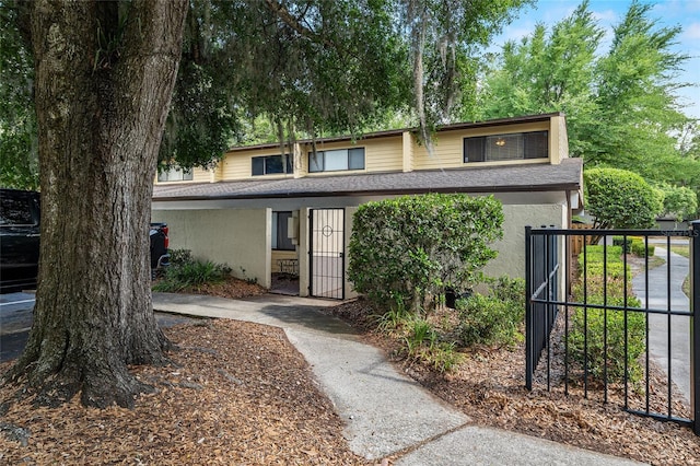 townhome / multi-family property with fence, a gate, stucco siding, and roof with shingles
