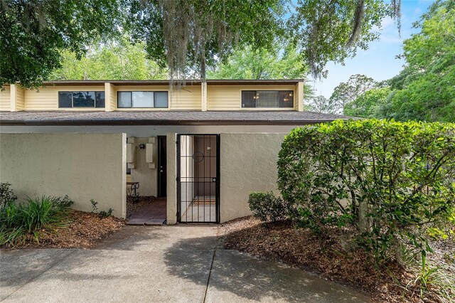 view of front of home featuring a shingled roof, a gate, and stucco siding