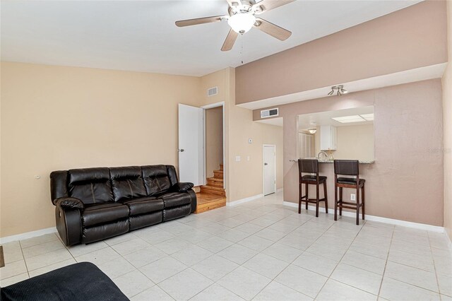 living room with visible vents, ceiling fan, light tile patterned floors, and stairway