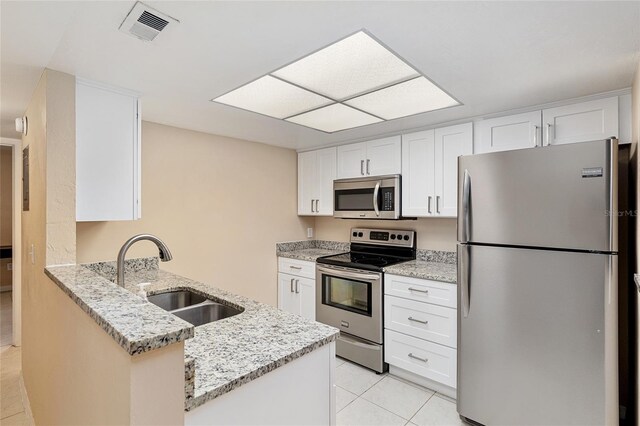kitchen with visible vents, a sink, light tile patterned floors, a peninsula, and stainless steel appliances