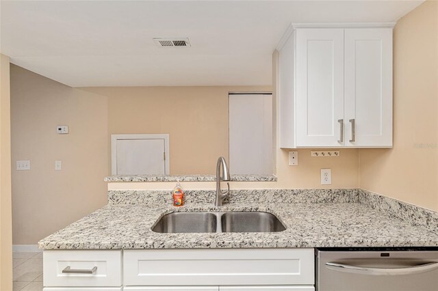 kitchen featuring white cabinets, light stone countertops, a sink, dishwasher, and a peninsula