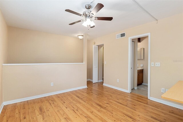 empty room featuring light wood-style floors, a ceiling fan, baseboards, and visible vents