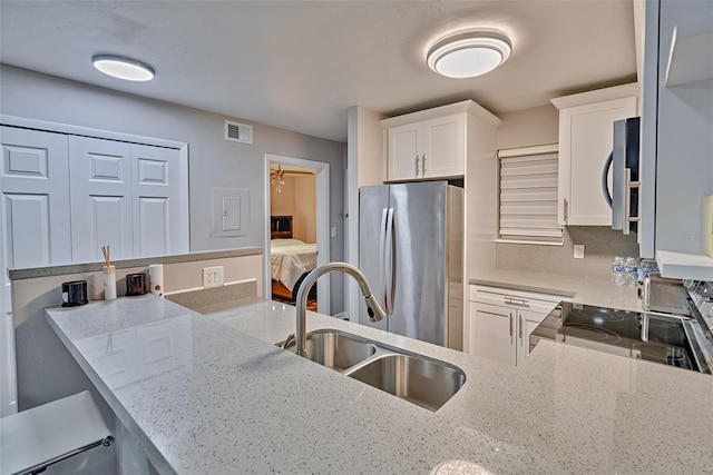 105 SE 16th Ave Unit N103, Gainesville, FL 32601 - kitchen featuring freestanding refrigerator, range, light stone counters, white cabinets, and a peninsula