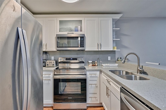 105 SE 16th Ave Unit N103, Gainesville, FL 32601 - kitchen featuring appliances with stainless steel finishes, open shelves, white cabinets, and glass insert cabinets