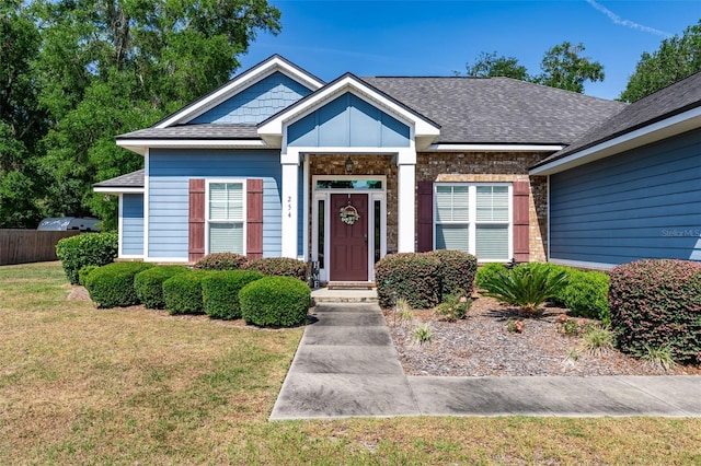 view of front of property with fence, a shingled roof, and a front lawn