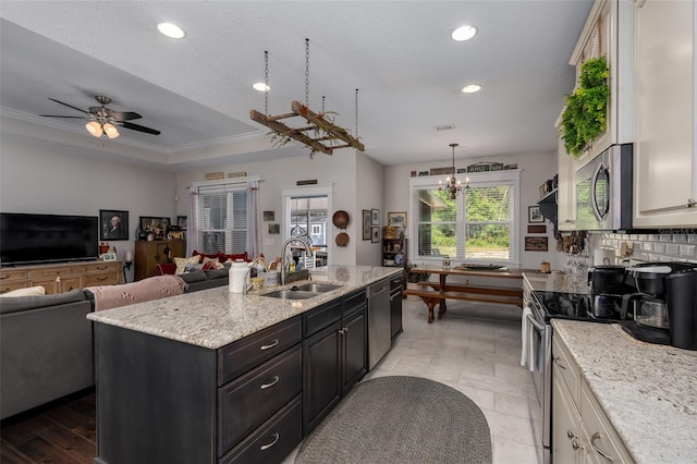 kitchen with a kitchen island with sink, light stone countertops, a sink, stainless steel appliances, and recessed lighting