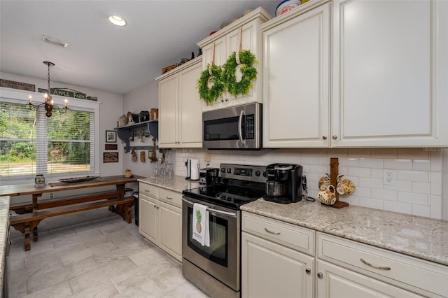 kitchen featuring backsplash, visible vents, light stone counters, a chandelier, and stainless steel appliances