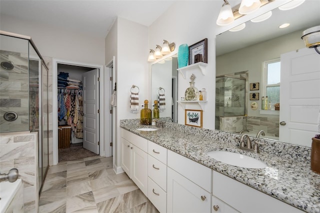 full bathroom featuring double vanity, a sink, a stall shower, and a spacious closet