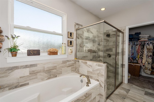 full bath featuring a garden tub, a walk in closet, and a shower stall