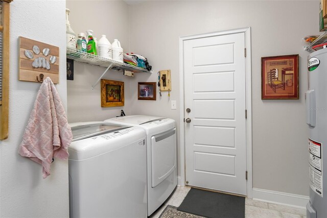 laundry area featuring light tile patterned floors, water heater, laundry area, and washing machine and clothes dryer