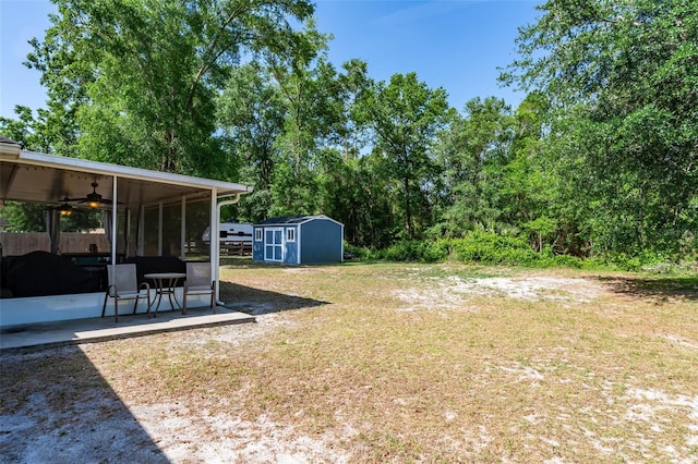 view of yard with a sunroom, a ceiling fan, a patio area, a storage shed, and an outbuilding