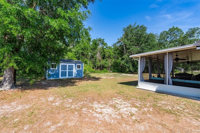view of yard with a storage unit, a ceiling fan, a sunroom, and an outdoor structure