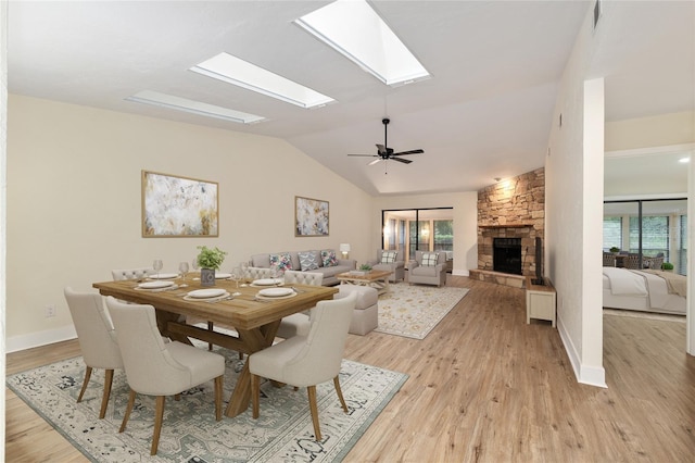 1612 NW 19th Cir, Gainesville, FL 32605 - dining area with baseboards, light wood finished floors, a stone fireplace, and lofted ceiling with skylight