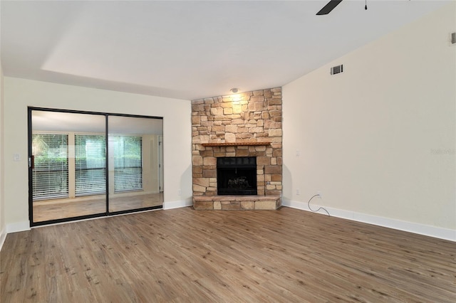 1612 NW 19th Cir, Gainesville, FL 32605 - unfurnished living room with ceiling fan, visible vents, a stone fireplace, and wood finished floors