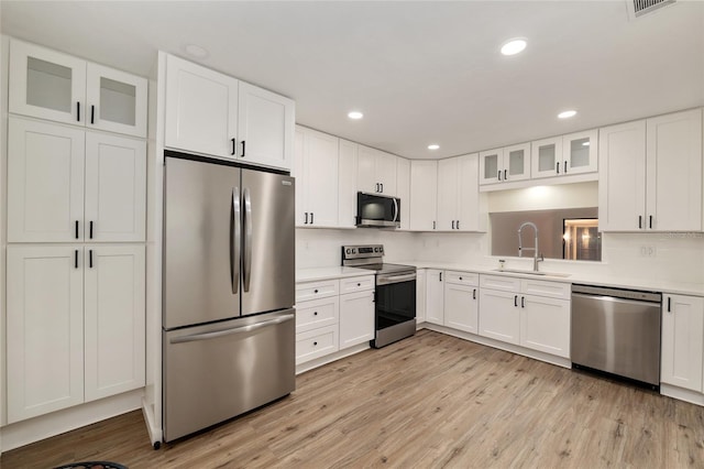 1612 NW 19th Cir, Gainesville, FL 32605 - kitchen with a sink, light countertops, light wood-style flooring, stainless steel appliances, and white cabinetry