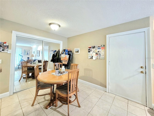 dining room featuring light tile patterned floors, baseboards, and a textured ceiling