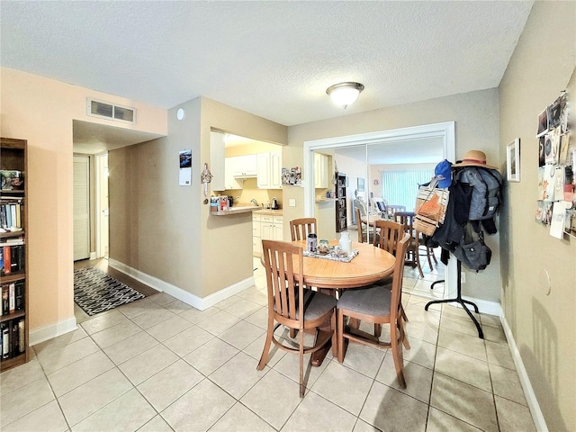 dining space featuring a textured ceiling, light tile patterned floors, and baseboards