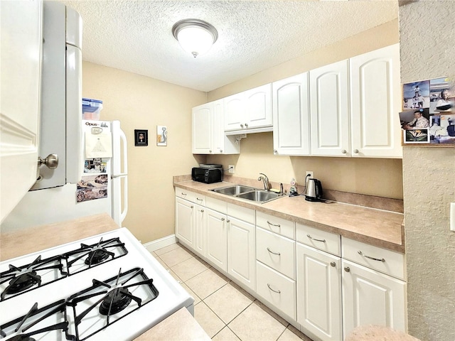 kitchen with a sink, white range with gas cooktop, white cabinetry, light tile patterned flooring, and light countertops